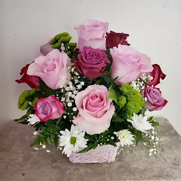 Pink and red rose bouquet in a small basket with white daisies