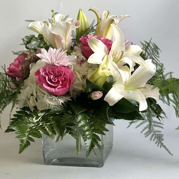 Pink roses and white lilies in a clear glass vase