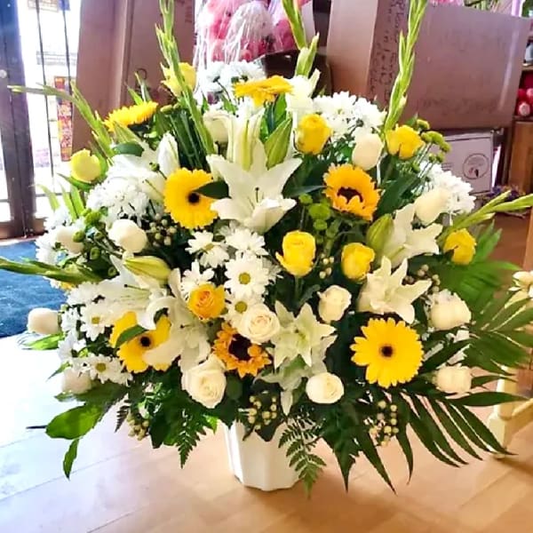 Large white and yellow floral arrangement in a white vase