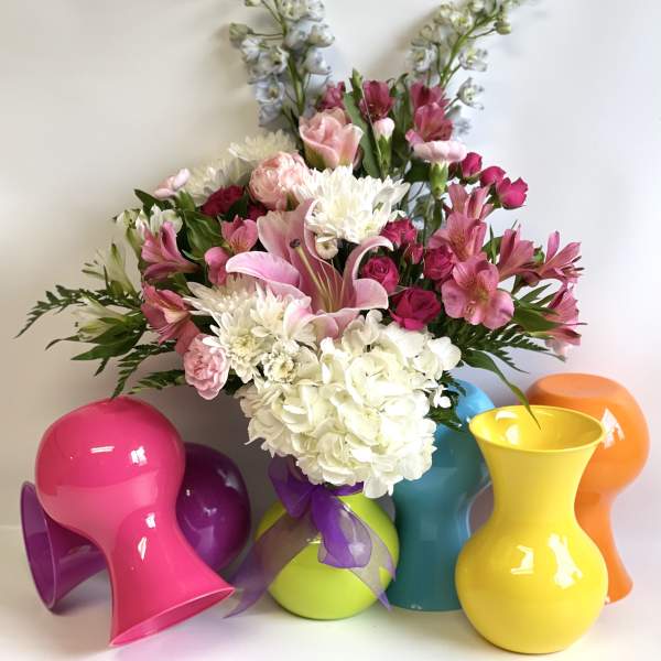 Mixed pink and white flower arrangement in colorful vases