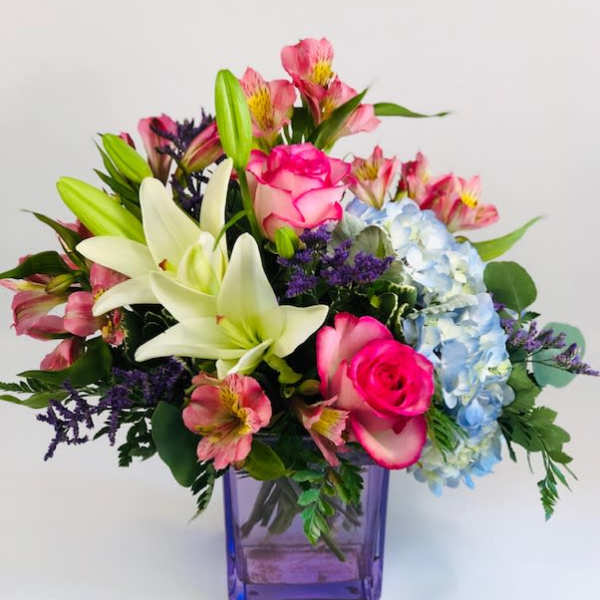 Mixed bouquet with lilies, roses, hydrangea, and alstroemeria in a purple vase