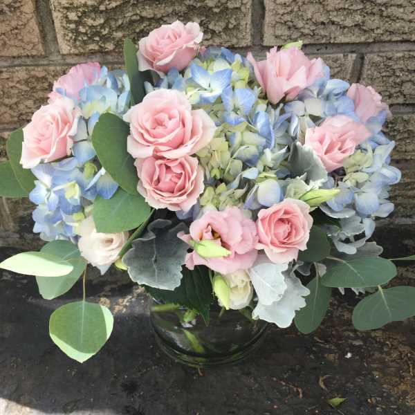 Pink roses and blue hydrangeas in a glass vase