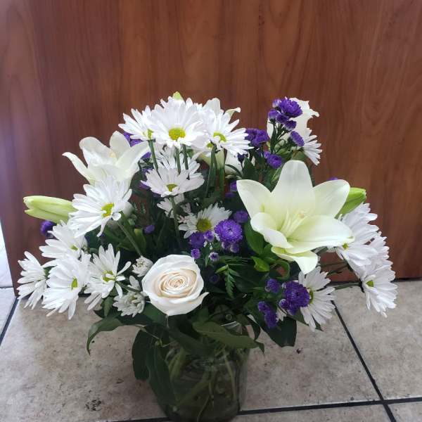 White daisies, lilies, and a rose in a glass vase