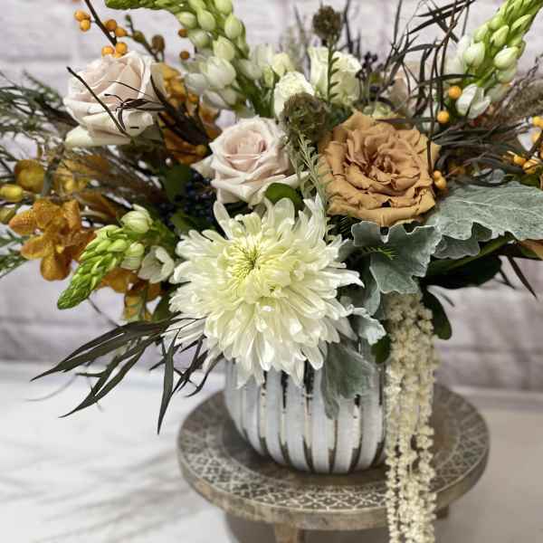 Mixed floral arrangement in a striped vase with white and tan blooms