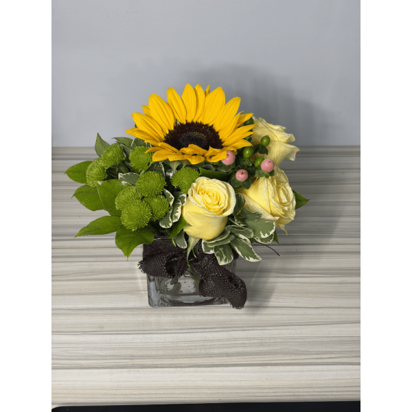 Sunflower and yellow rose arrangement in a square glass vase