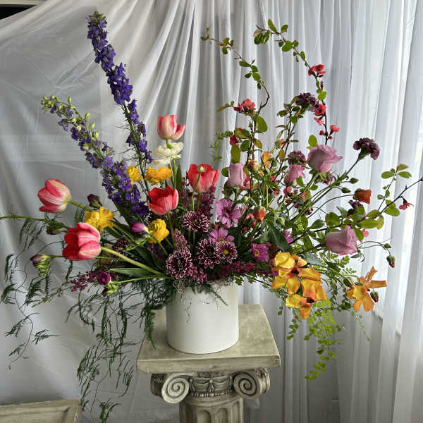 Tall mixed bouquet in a white vase with pink, purple, and yellow flowers