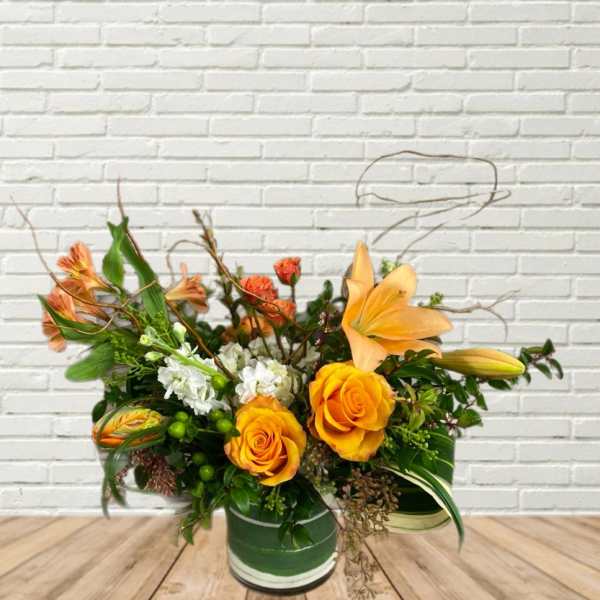 Orange roses and lilies arranged in a green vase
