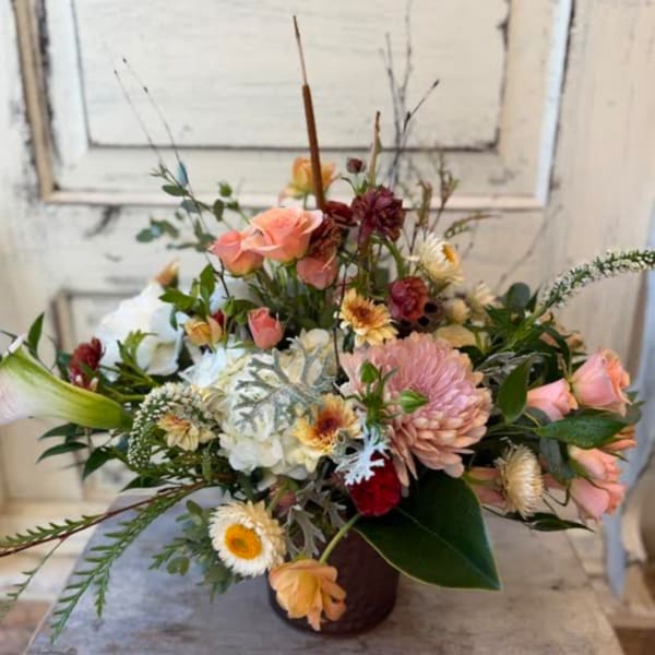 Mixed bouquet in a dark vase with peach, white, and burgundy flowers