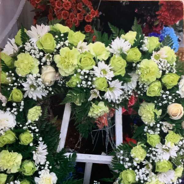 Large floral wreath on a white stand with lime green and white flowers