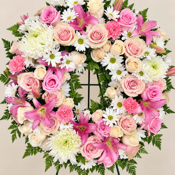 Heart-shaped floral wreath with pink roses, white daisies, and lilies