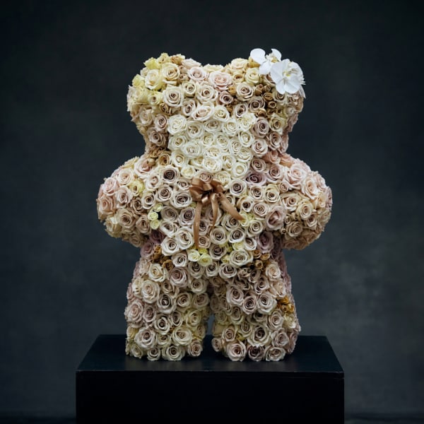 Teddy bear made of cream and blush roses with a ribbon bow