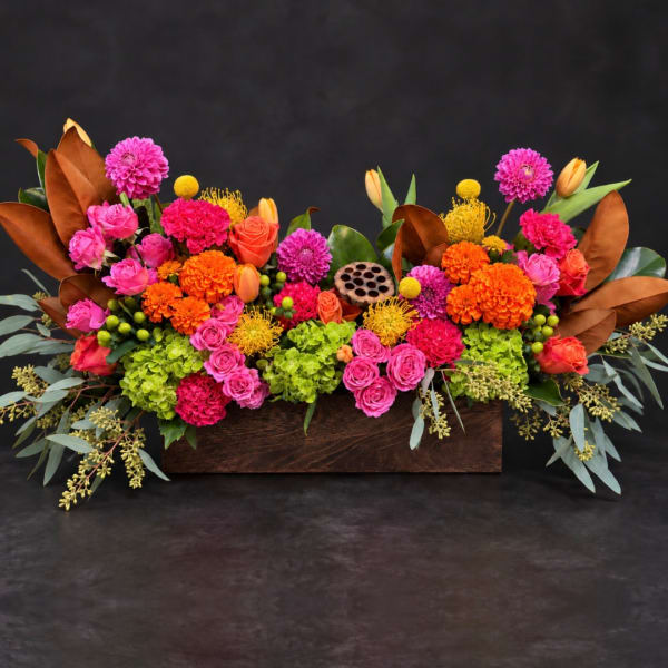 Bright mixed flower arrangement in a wooden box with pink, orange, and yellow blooms