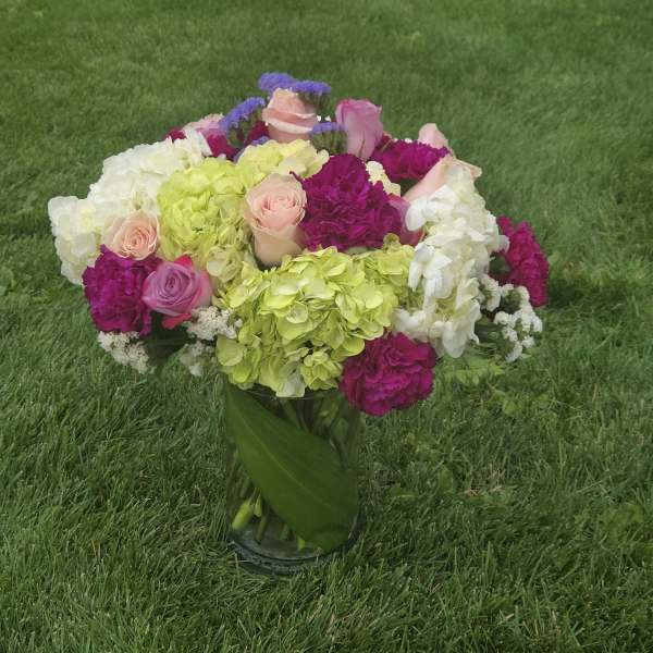 Colorful bouquet of roses, hydrangeas, and carnations in a glass vase
