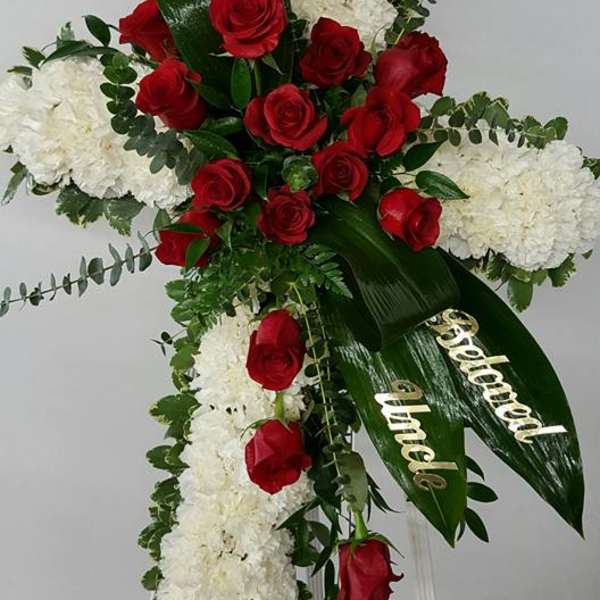 Cross-shaped floral spray with red roses and white blooms on an easel