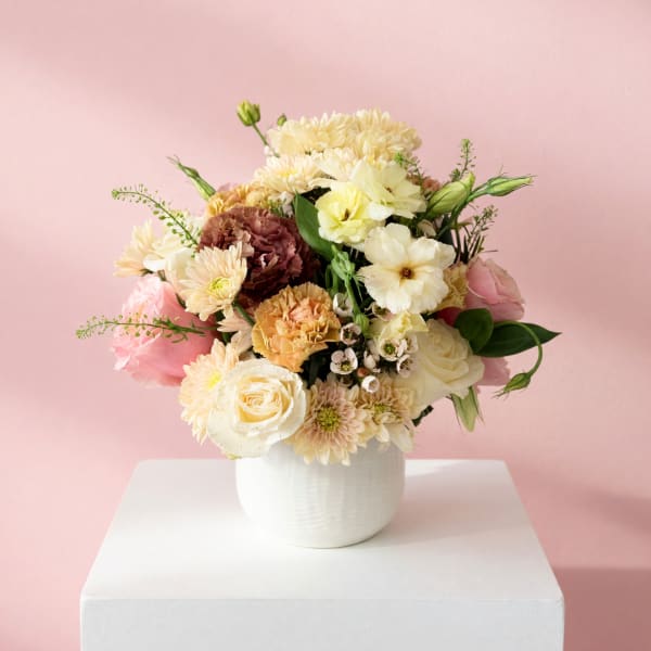 Mixed pastel bouquet in a white vase on a pedestal