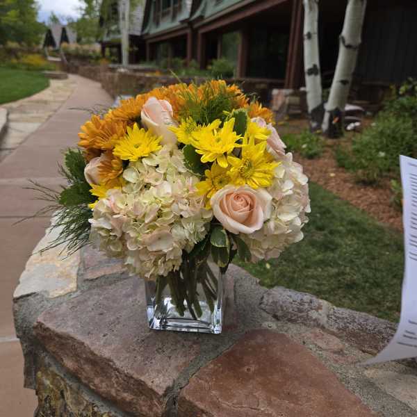 Bouquet of yellow and blush flowers in a clear glass vase