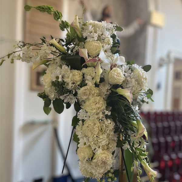 Large white floral cross arrangement on a stand