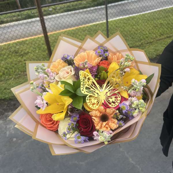 Colorful mixed bouquet with roses, lilies, and a butterfly decoration