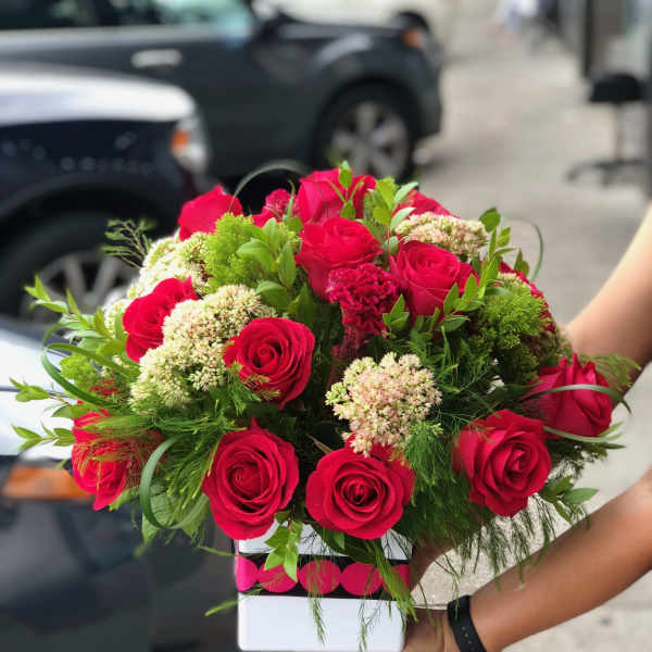 Bouquet of red roses and green filler in a white box