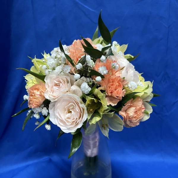 Bouquet of pale roses, peach carnations, and white filler flowers in a vase