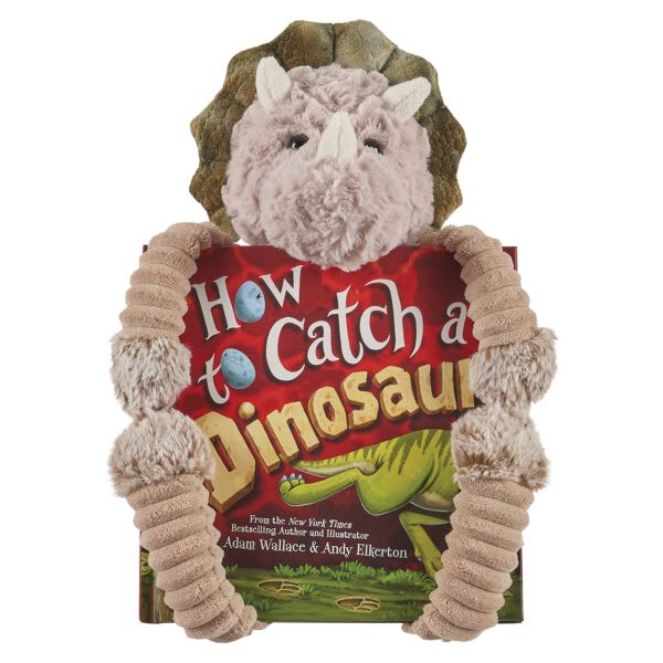 Plush triceratops toy hugging a dinosaur book