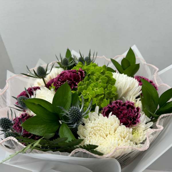 Bouquet of white and magenta flowers with green accents in pink-edged wrap