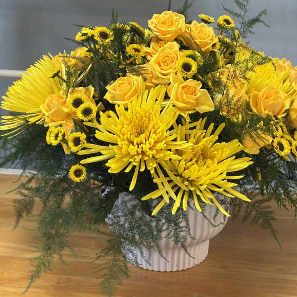 Yellow roses and chrysanthemums arranged in a white vase
