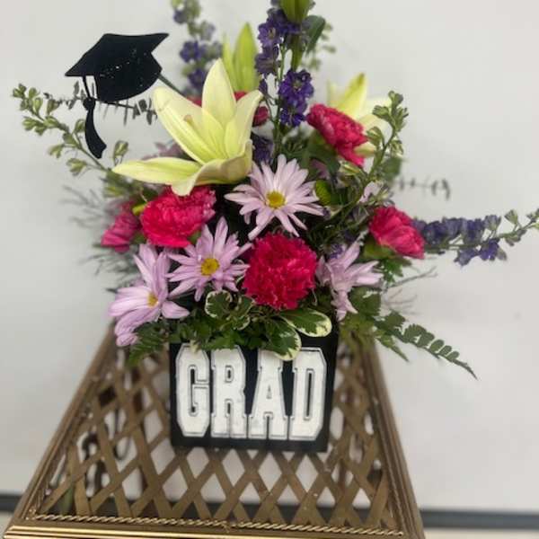 Graduation flower arrangement with a black cap decoration and "GRAD" sign