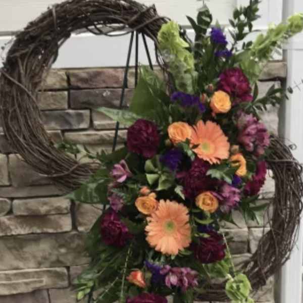 Floral standing spray with orange and purple flowers on a wreath stand