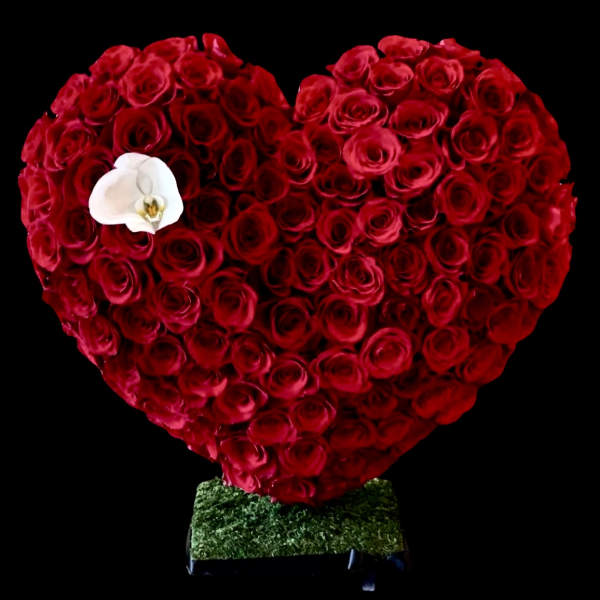 Heart-shaped arrangement of red roses with a white orchid accent