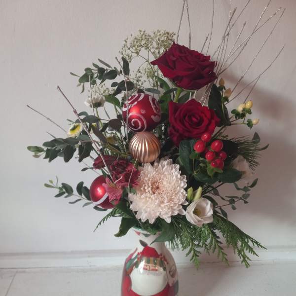 Red roses and white flowers arranged in a Santa-themed vase