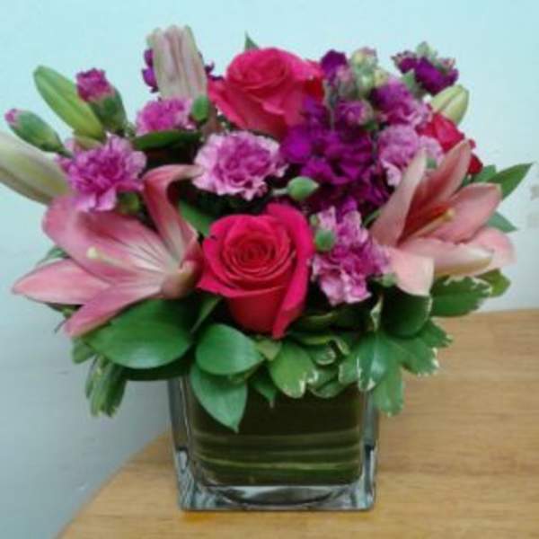 Pink and purple flower arrangement in a square glass vase