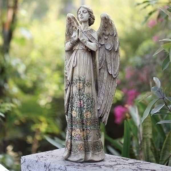 Stone angel statue with floral details standing in a garden