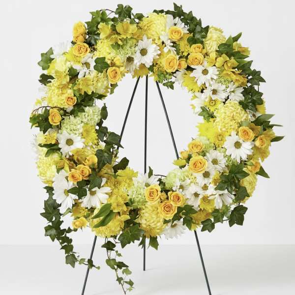 Yellow and white floral wreath on a black stand