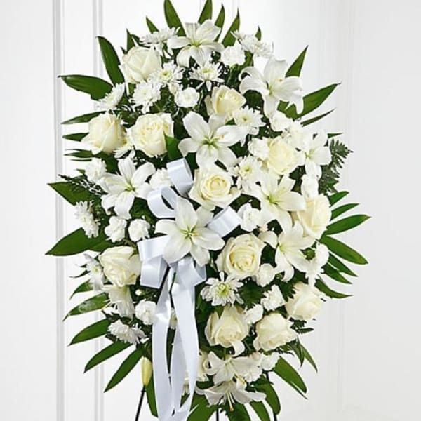 White floral standing spray with roses and lilies on an easel
