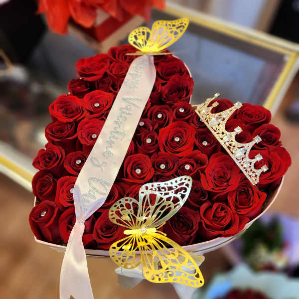 Heart-shaped bouquet of red roses with butterfly decorations and a ribbon