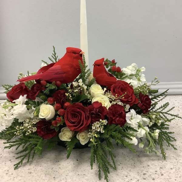 Red cardinal figurines in a floral centerpiece with a tall white candle