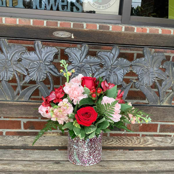 Red and pink flower arrangement in a mosaic vase