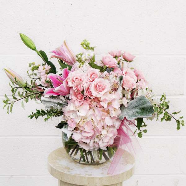 Pink roses and lilies arranged in a glass vase
