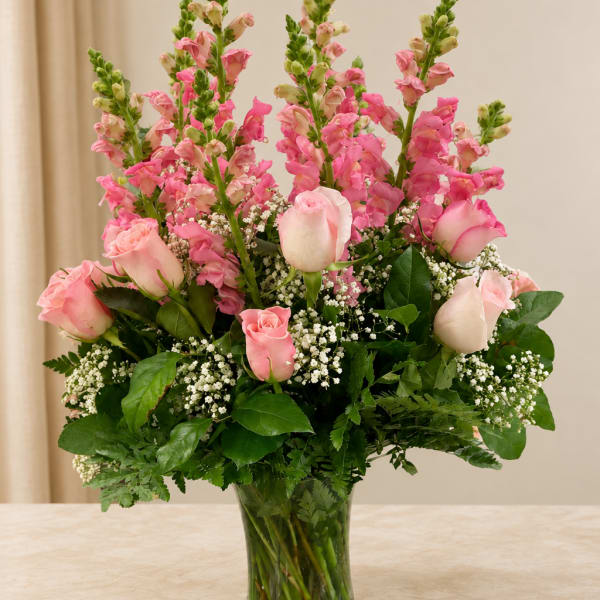 Pink roses and snapdragons arranged in a clear glass vase