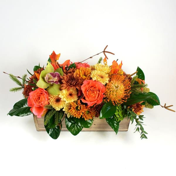 Autumn floral arrangement in a wooden box with orange and yellow blooms