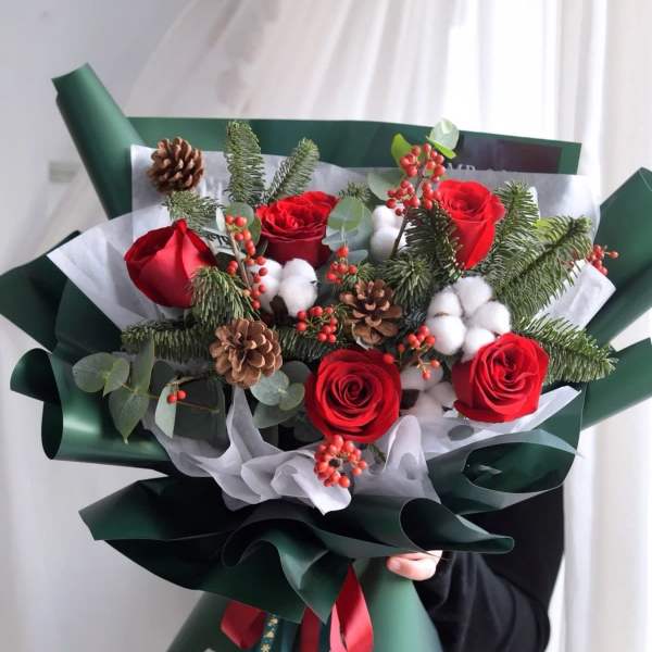 Bouquet of red roses with pinecones and cotton in dark green wrap