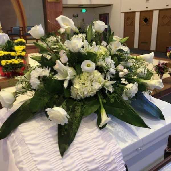 White funeral casket spray with calla lilies and roses