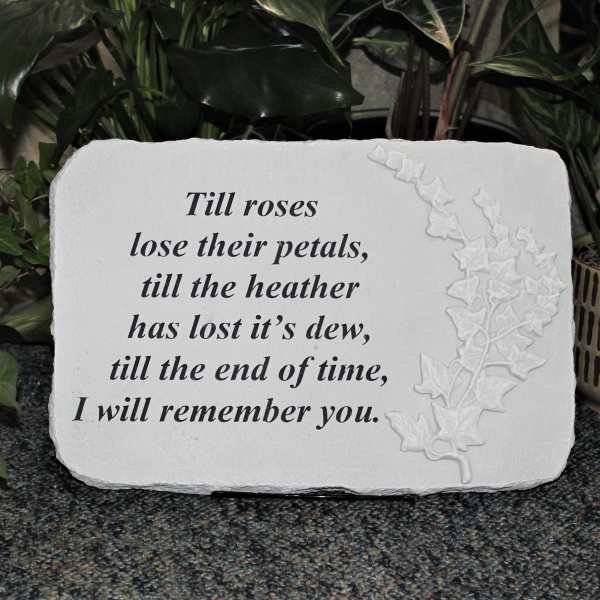 White memorial plaque with an engraved quote and floral relief