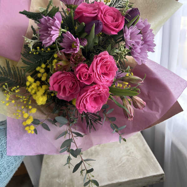 Bouquet of pink roses and purple daisies with yellow filler flowers
