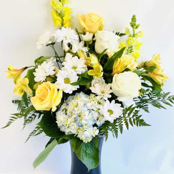 Yellow and white flowers arranged in a blue vase
