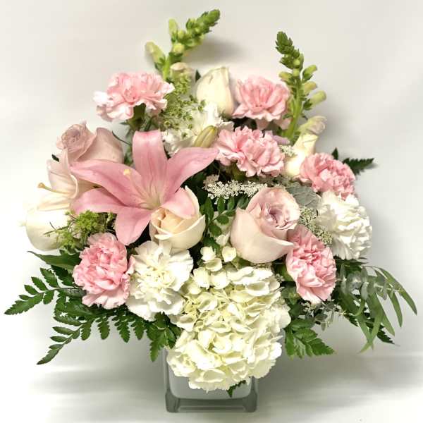 Pink and white floral arrangement in a square glass vase