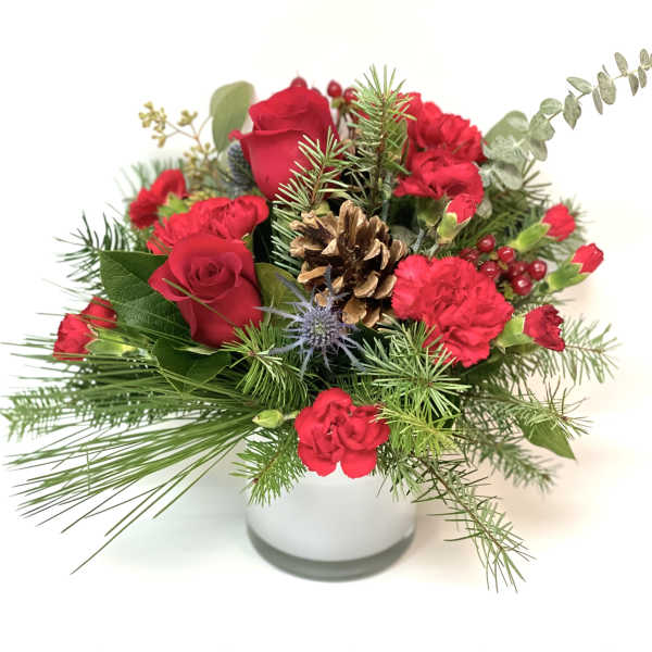 Red roses and carnations in a white vase with pine and a pinecone