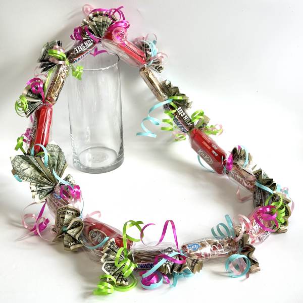 Candy and cash garland wrapped around a clear glass vase