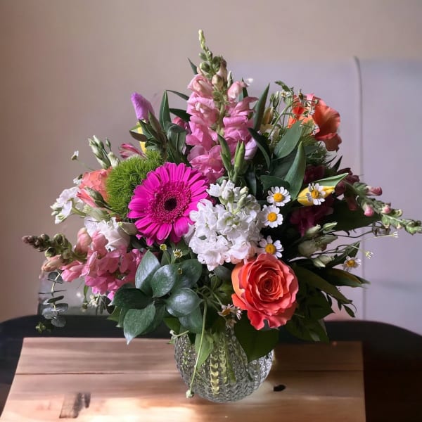 Mixed bouquet in a textured glass vase with pink, white, and orange blooms